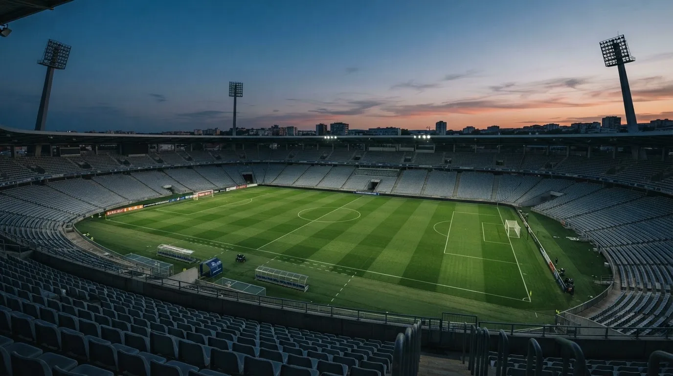 An empty football stadium with floodlight masts at dusk