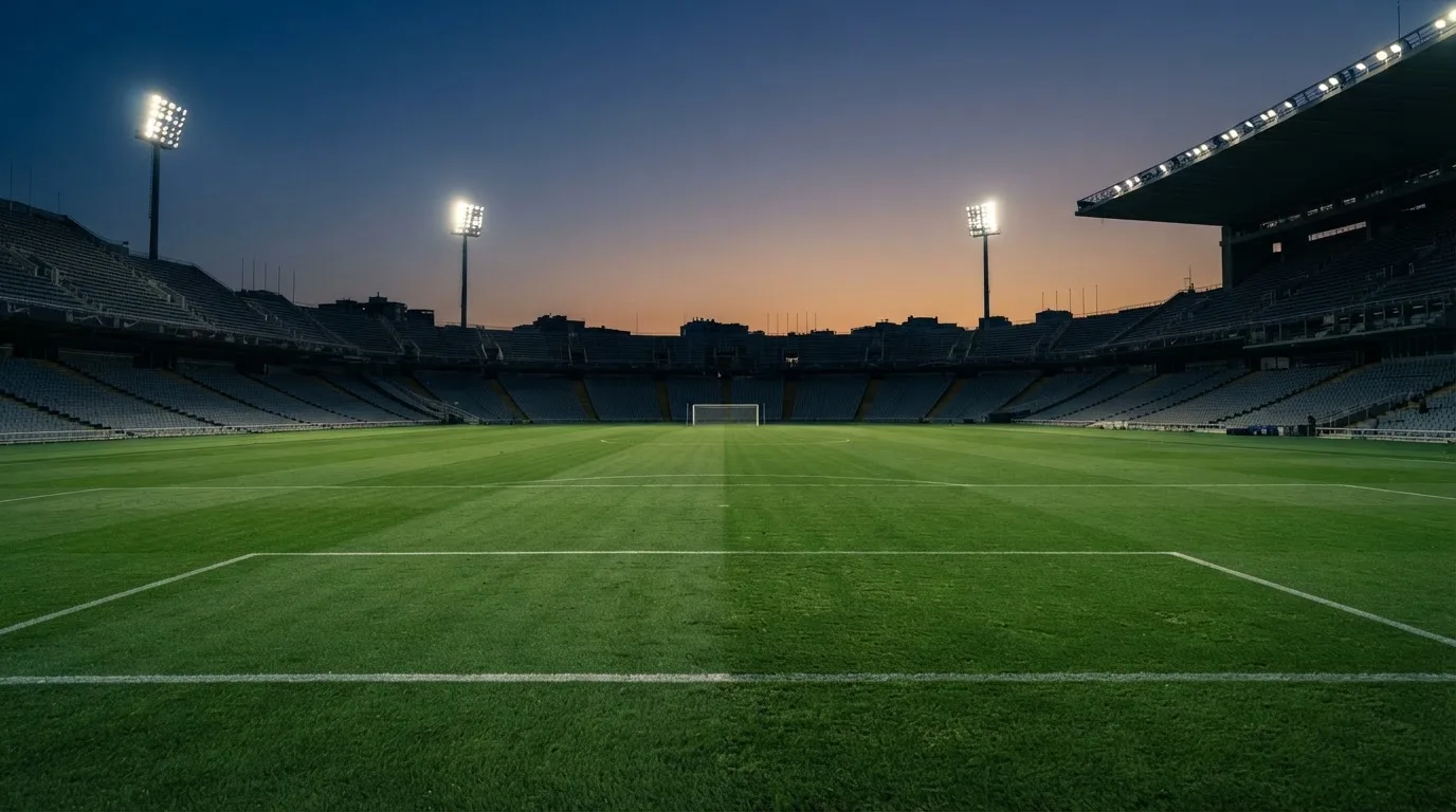 An empty football stadium with floodlight masts at dusk