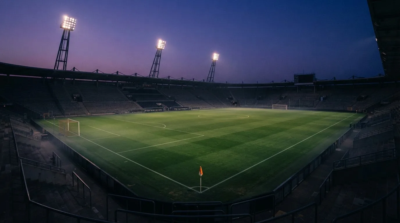 An empty football stadium with floodlight masts at dusk