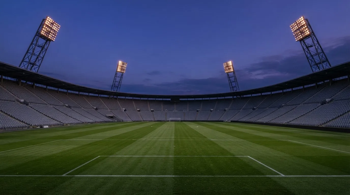 An empty football stadium with floodlight masts at dusk