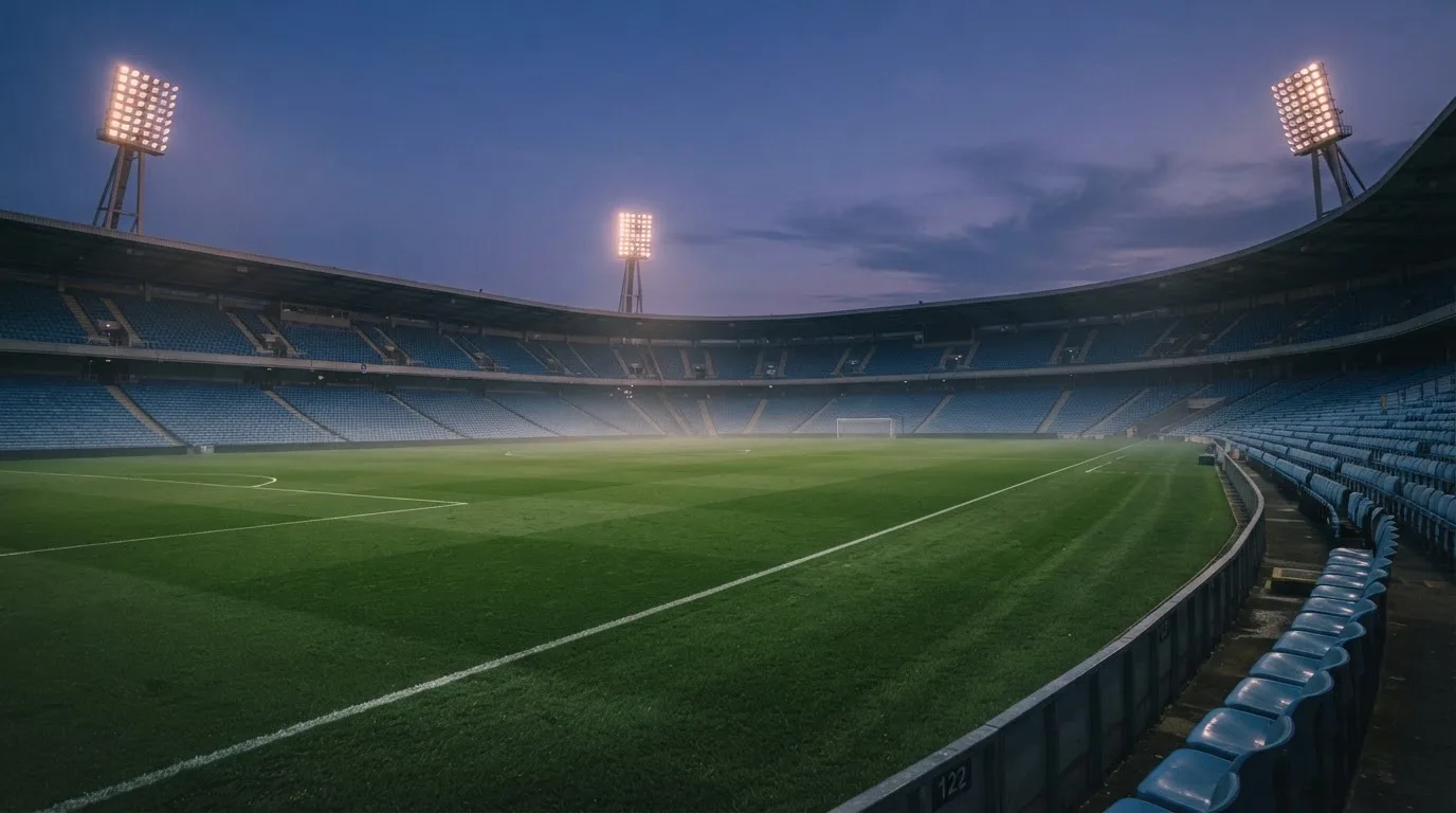 An empty football stadium with floodlight masts at dusk