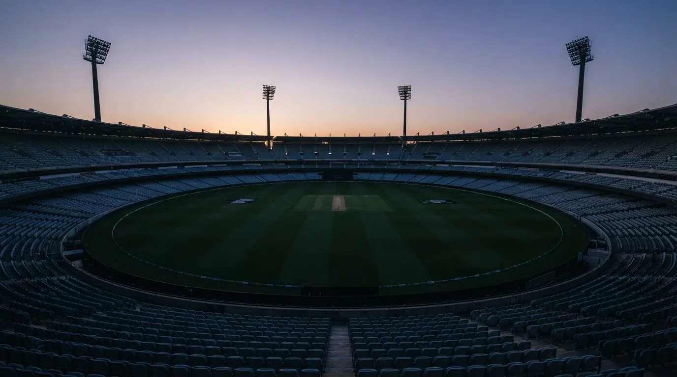 An empty football stadium with floodlight masts at dusk