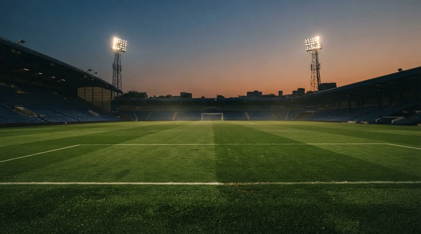 An empty football stadium with floodlight masts at dusk