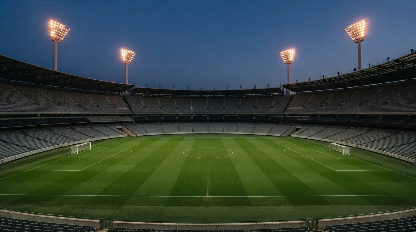 An empty football stadium with floodlight masts at dusk