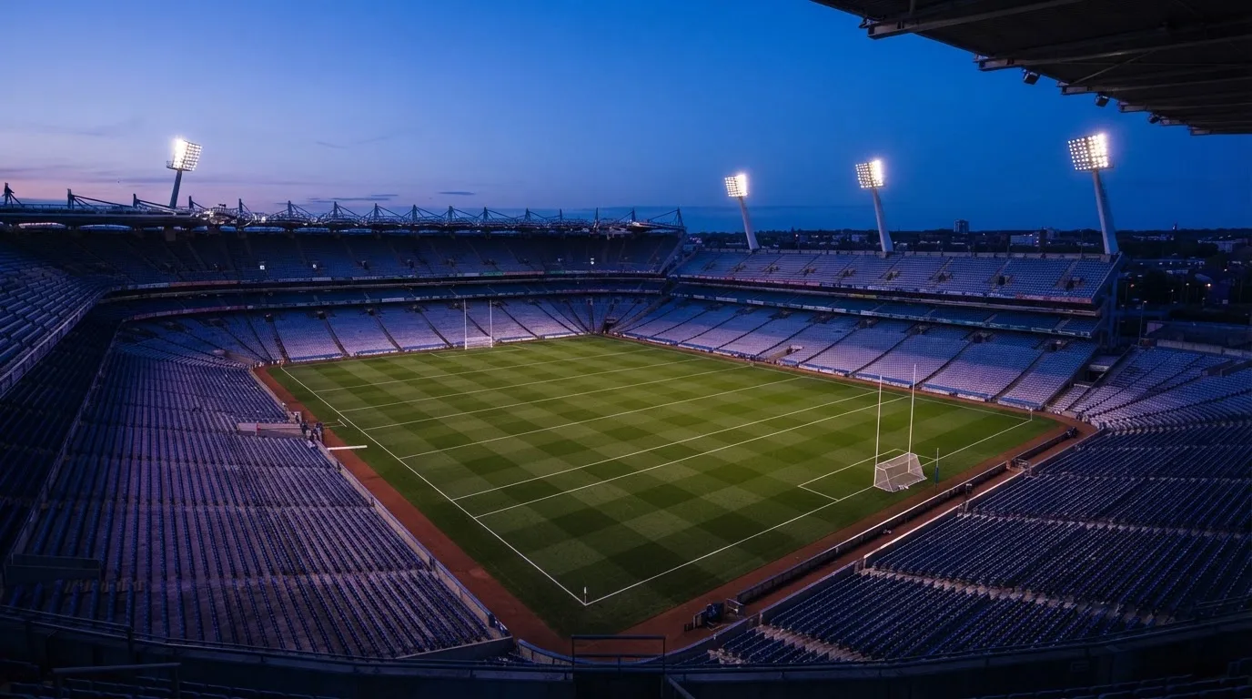 An empty football stadium with floodlight masts at dusk