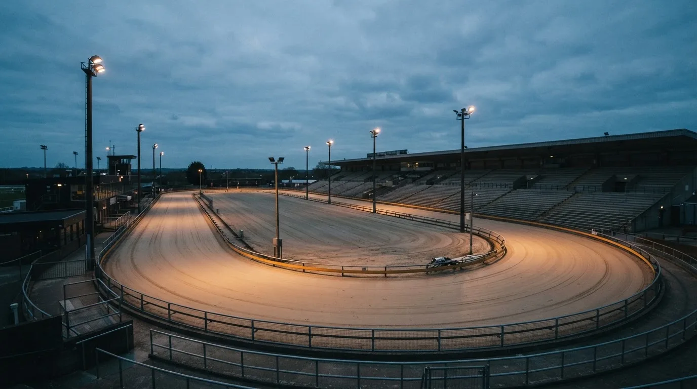 An empty football stadium with floodlight masts at dusk