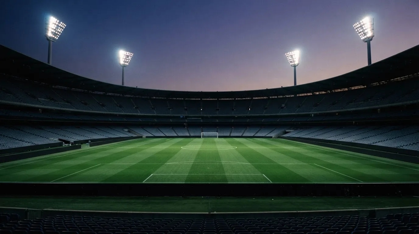An empty football stadium with floodlight masts at dusk